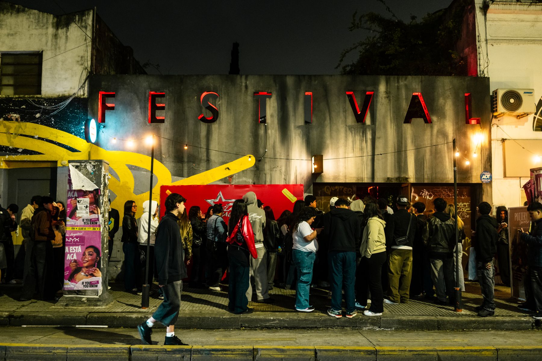 Fila de fans en la puerta del lugar, de noche