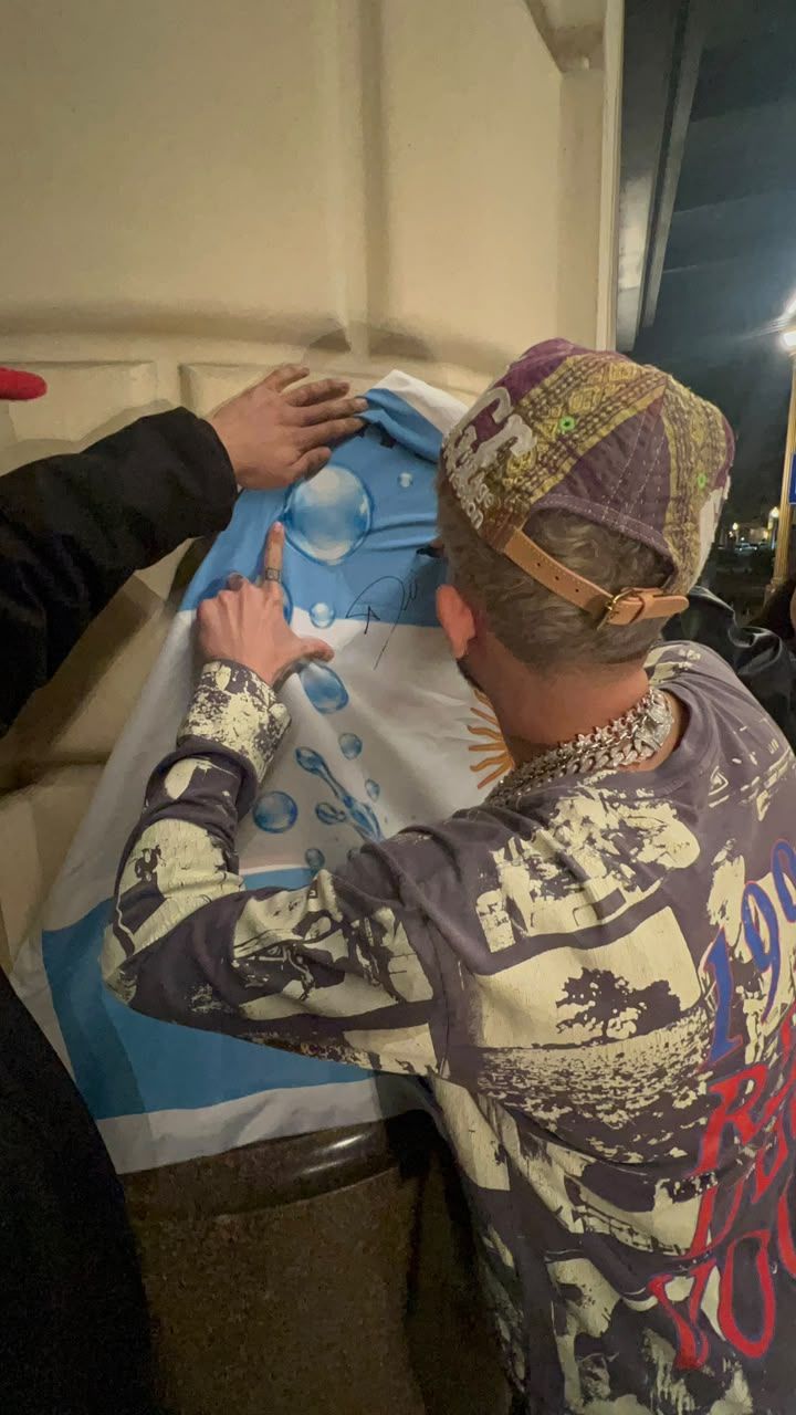 Dei V firmando la bandera argentina del fan club