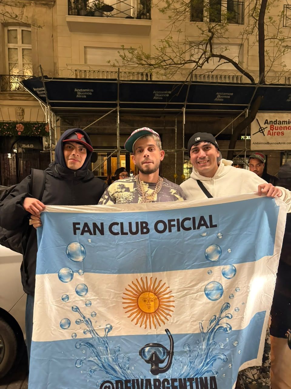 Dei V con integrantes del fan club sosteniendo la bandera Fan Club Oficial