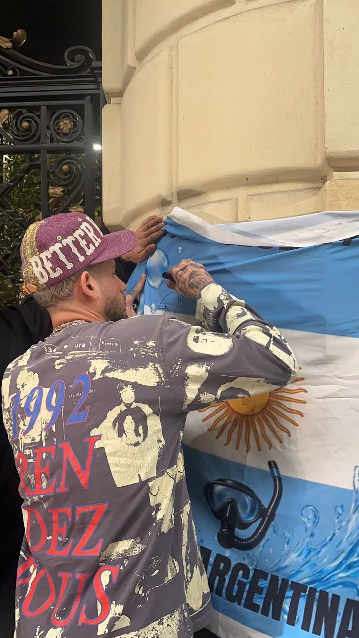 Dei V firmando la bandera apoyada en una pared